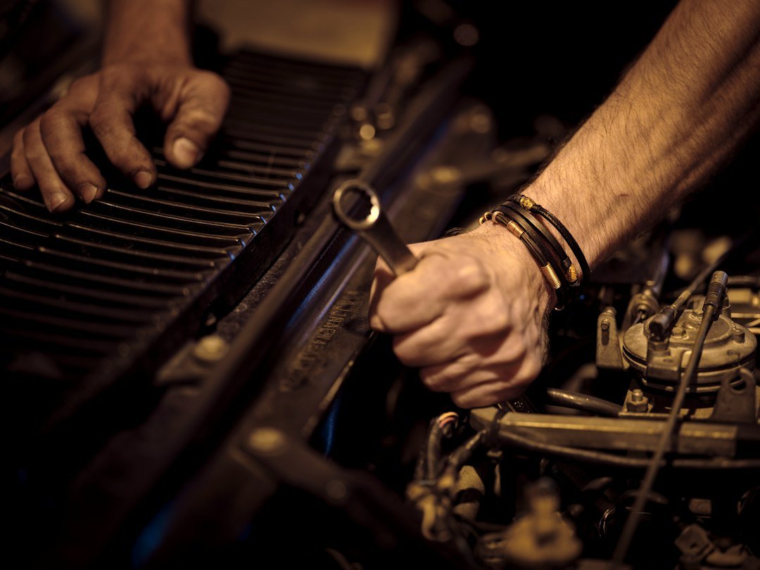 Manos trabajando en el motor de un vehículo con una llave